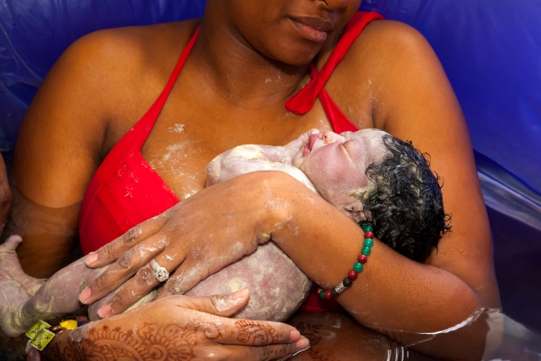 a mother using a midwife for a hospital birth holds her newborn in her arms after a water birth