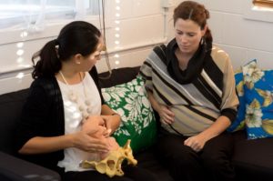 midwife holding model of pelvis educated pregnant woman on birth