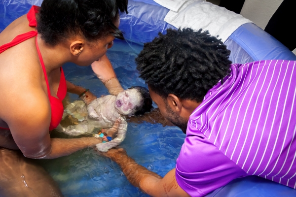 using a midwife for their hospital birth allowed the dad to catch his baby during water birth.