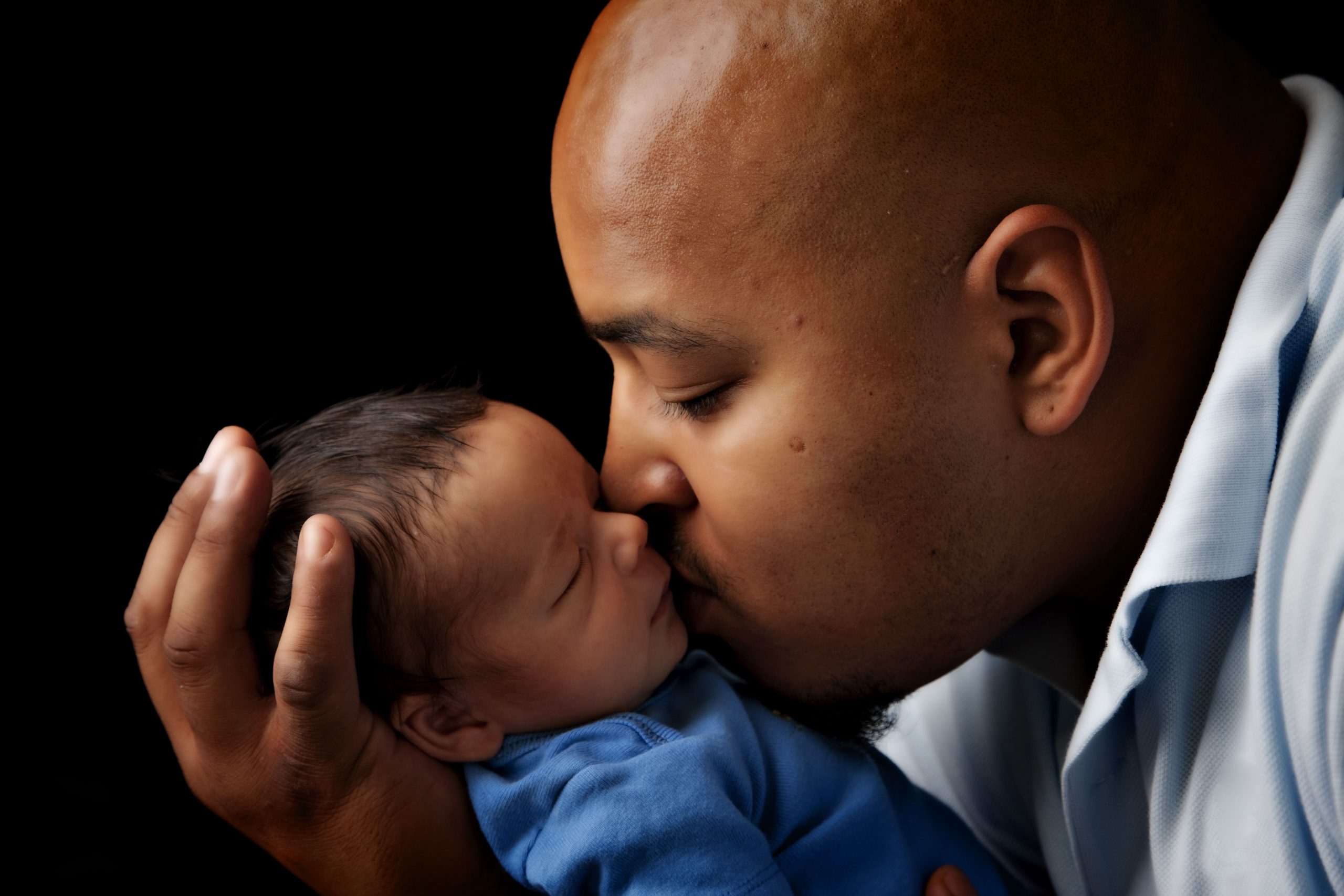 African America dad kissing his newborn after getting birth support from Silver Spring Doula during covid-19